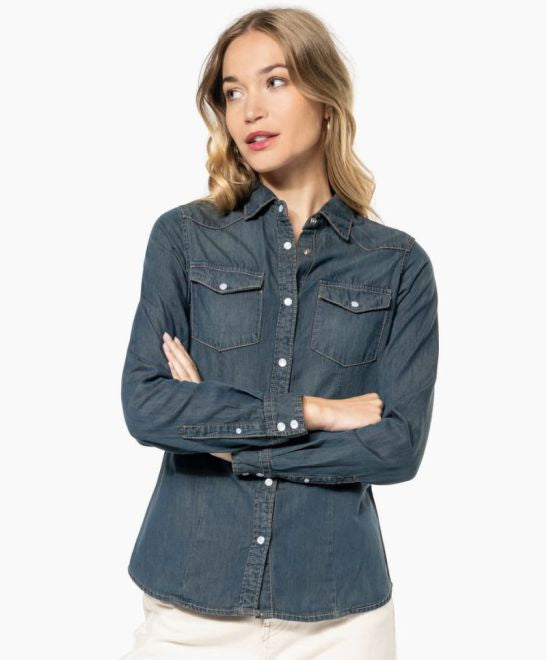 Ženska denim srajca z dolgimi rokavi Kariban K518, modra, s spuščenim ovratnikom in vidnimi šivi, prikazana v celoti.